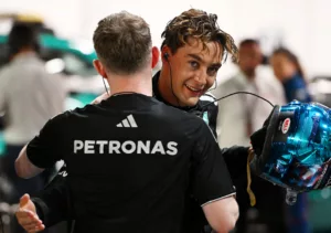 George Russell embraces his mechanic after securing pole position at the Singapore Grand Prix 2025, visibly sweating and emotional.